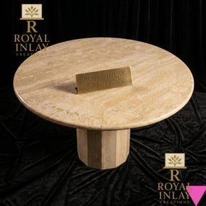 Może przedstawiać: Okrągły, beżowy marmurowy stół z geometryczną podstawą. Stół posiada napis "ROYAL INLAY CREATIONS" na małym mosiężnym znaku. Stół stoi na czarnym tle, z logo Royal Inlay w rogach.