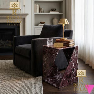 Puede incluir: Una mesa auxiliar moderna con dise&ntilde;o geom&eacute;trico, hecha de m&aacute;rmol burdeos con vetas blancas. La mesa est&aacute; junto a un sill&oacute;n gris oscuro y una l&aacute;mpara dorada. El texto "ROYAL INLAY CREATIONS" es visible.