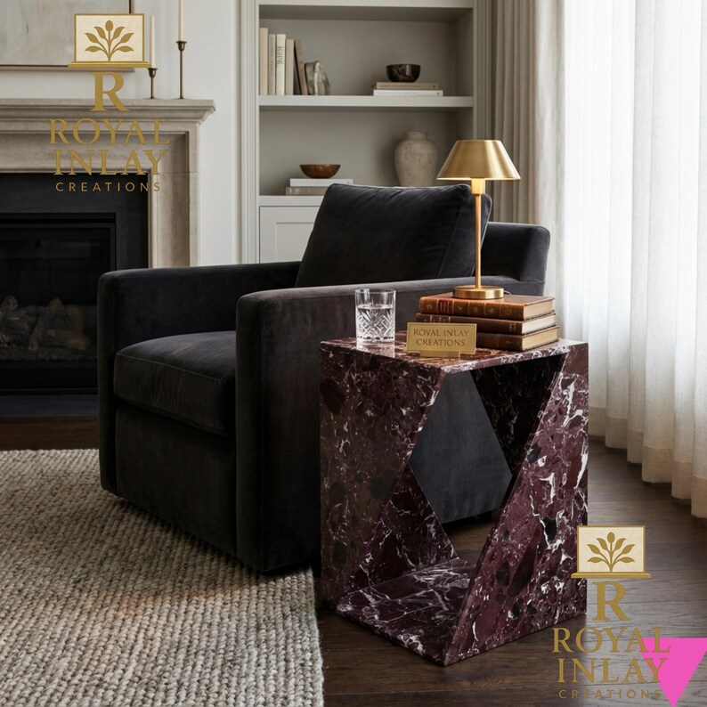 Puede incluir: Una mesa auxiliar moderna con dise&ntilde;o geom&eacute;trico, hecha de m&aacute;rmol burdeos con vetas blancas. La mesa est&aacute; junto a un sill&oacute;n gris oscuro y una l&aacute;mpara dorada. El texto "ROYAL INLAY CREATIONS" es visible.
