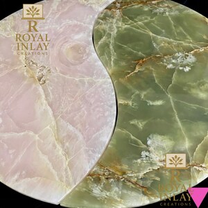 May include: A Yin Yang shaped decorative piece, featuring a light pink and green marble design. The pink side has white veining, while the green side has brown veining. The text "ROYAL INLAY CREATIONS" is visible.