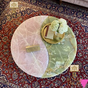 May include: A unique coffee table with a yin-yang design, featuring a pink and green marble top. A gold tray with a book and flowers sits on the green side. The table has the text "Royal Inlay Creations" on a small gold block.