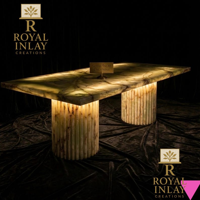 May include: A rectangular, illuminated onyx table with two cylindrical, ribbed supports. The table's surface has a marbled green and brown pattern. The table is lit from within, creating a warm glow. The text "Royal Inlay Creations" is visible.