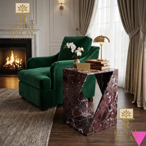 Puede incluir: Una escena de sal&oacute;n moderno con una chaise longue verde oscuro, una mesa auxiliar geom&eacute;trica de m&aacute;rmol y una l&aacute;mpara dorada. La mesa auxiliar tiene un dise&ntilde;o angular &uacute;nico y est&aacute; hecha de m&aacute;rmol rojo y blanco. La habitaci&oacute;n tambi&eacute;n incluye una chimenea y una alfombra.