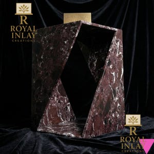 Puede incluir: Una mesa auxiliar geom&eacute;trica de m&aacute;rmol burdeos con vetas blancas. La mesa tiene un dise&ntilde;o &uacute;nico y abierto con lados angulados y una parte superior rectangular. La marca "ROYAL INLAY CREATIONS" se muestra en la parte superior e inferior.