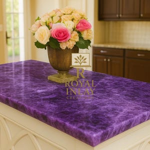Può includere: Un'isola cucina con un vivace piano di lavoro viola. Il piano di lavoro ha un aspetto marmorizzato ed è posto su una base bianca con finiture decorative. Un vaso di rose rosa e gialle è posto sul piano di lavoro. La cucina ha mobili in legno scuro ed elettrodomestici in acciaio inossidabile.