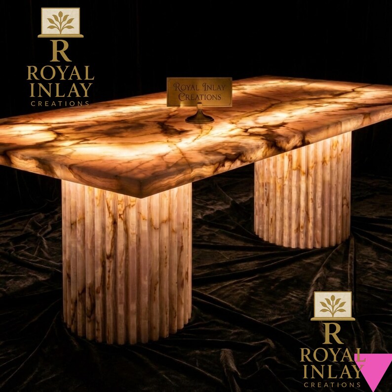 May include: A rectangular table with a glowing, translucent top and two cylindrical, fluted legs. The table's surface has a warm, amber color with brown veining. The table is illuminated from within, creating a soft glow. The table is branded with the text "Royal Inlay Creations".