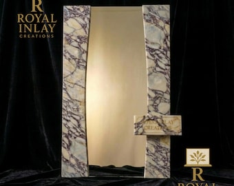May include: A rectangular mirror with a gold-colored surface, framed by marble-patterned borders. A small marble shelf is attached to the frame. The text "ROYAL INLAY CREATIONS" is visible.