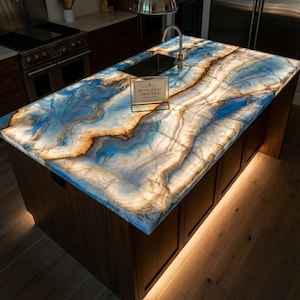 Op de afbeelding: Keuken eiland met een blauw, wit en goudkleurig aanrechtblad. Het aanrechtblad heeft een uniek, wervelend patroon. Het eiland heeft donkerbruine kasten en een ingebouwde spoelbak. De tekst "ROYAL INLAY CREATIONS" is zichtbaar.