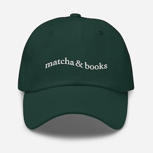 Może przedstawiać: Ciemnozielona czapka z daszkiem z haftowanym białym tekstem "matcha & books".