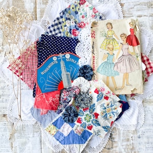 May include: A collection of vintage sewing items including a Woolworth needle book, a paper sewing pattern envelope with illustrations of four dresses, various fabric scraps in floral, gingham, and polka dot patterns, and small fabric rosettes.