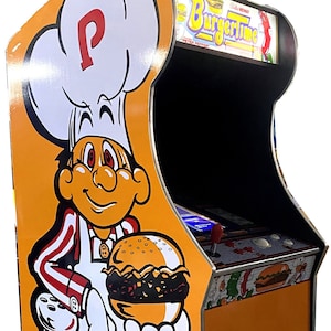 Könnte beinhalten: Ein orangefarbener BurgerTime-Spielautomat mit einem Koch, der einen Burger hält. Der Automat hat das Logo des Spiels und einen Münzschlitz. Der Koch trägt einen weißen Hut mit einem roten "P".