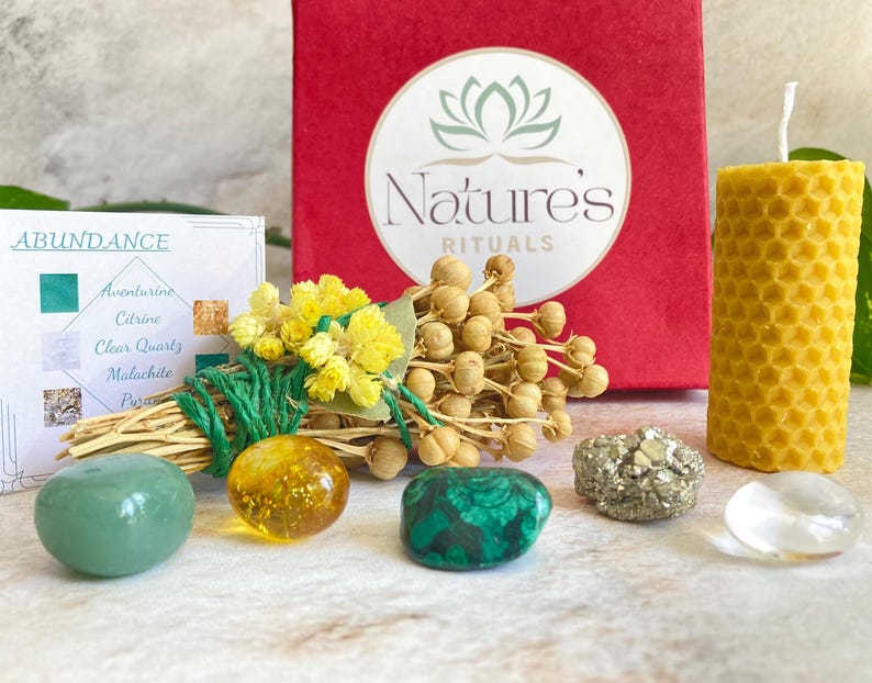 May include: A green and gold abundance ritual kit with a small box, a candle, crystals, and dried flowers. The box says "Nature's Rituals" and the card says "Abundance".