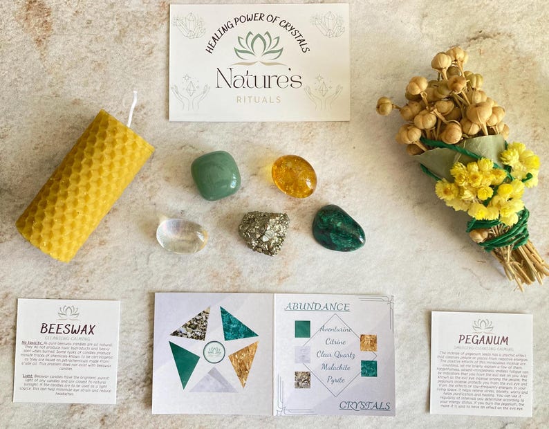 May include: A green and gold crystal kit for abundance rituals. The kit includes a beeswax candle, a bundle of dried flowers, and five crystals: aventurine, citrine, clear quartz, malachite, and pyrite. The kit also includes two cards with information about the crystals and their uses.