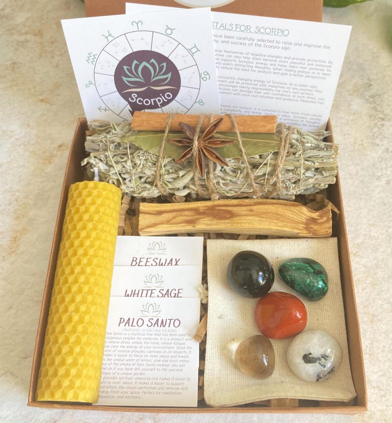 May include: A brown box with a white sage smudge stick, a beeswax candle, palo santo sticks, and a small bag of crystals. The box also includes a card with the text "Crystals for Scorpio".