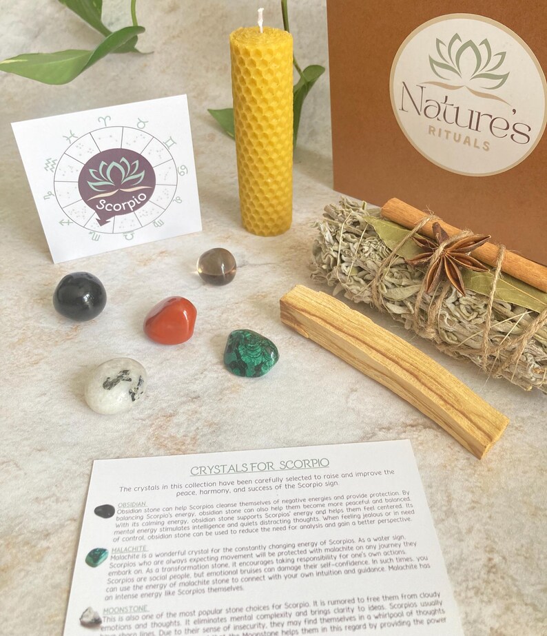 May include: A set of crystals for Scorpio zodiac sign, including obsidian, malachite, and moonstone. The set also includes a yellow beeswax candle, a bundle of sage, and a palo santo stick. The crystals are arranged on a white surface with a card that reads "Crystals for Scorpio".