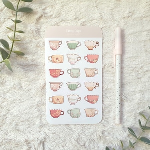 Könnte beinhalten: Ein Bogen mit Aufklebern mit 18 verschiedenen Teetassen-Designs. Die Teetassen sind in verschiedenen Farben, darunter rosa, grün und blau, und haben Blumenmuster. Die Aufkleber sind mit "Fancy Cups" beschriftet.