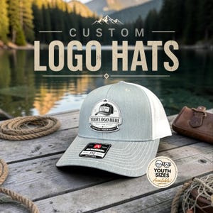 May include: A light gray and white trucker hat featuring a central patch with the text YOUR LOGO HERE and a small graphic of a hat. The brim has a black Richardson 112 sticker, and a circular badge indicates YOUTH SIZES Available.