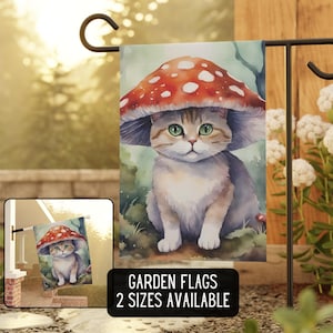 May include: A watercolor illustration of a cat wearing a red and white mushroom cap. The cat is sitting on a green and brown background. The image is a garden flag with the text "GARDEN FLAGS 2 SIZES AVAILABLE".