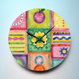 May include: Round wall clock with a colorful, patchwork design. The clock face features a grid of squares in various colors, including pink, green, yellow, and orange, with a central flower and a purple fruit. Black clock hands indicate the time.