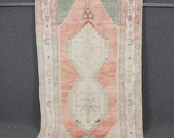 Puede incluir: Una alfombra rectangular vintage con un patrón de diamante central en tonos melocotón, verde y crema. La alfombra presenta intrincados diseños de borde y una apariencia desgastada, lo que sugiere edad y uso. La alfombra se muestra verticalmente.