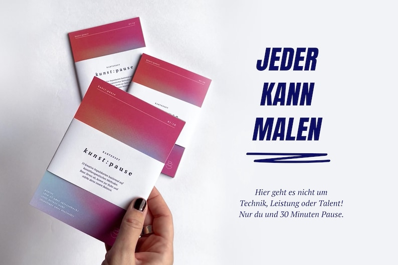 May include: Three booklets with a white and gradient pink and purple cover are held by a hand. The text "kunst:pause" is visible on the front cover. The text "JEDER KANN MALEN" is displayed in blue on the right side.