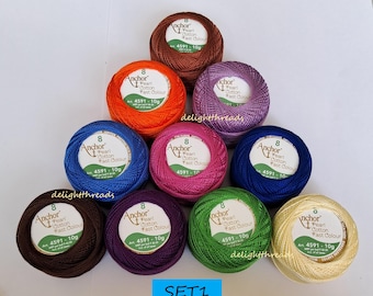 May include: A collection of ten colorful balls of Anchor Pearl Cotton thread, each with a label indicating the product details. The thread colors include brown, orange, purple, pink, blue, green, and cream. The text "SET1" is visible at the bottom.