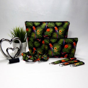 Gift set in black, green red and blue with multi coloured parrots printed on the fabric. The set comprises of a make up bag with black zip, Larger wash bag with black zip, 3 sizes of keyrings, small, medium and large. Two hair scrunchies.