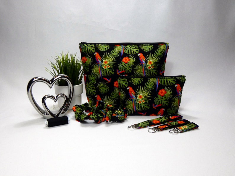 Gift set in black, green red and blue with multi coloured parrots printed on the fabric. The set comprises of a make up bag with black zip, Larger wash bag with black zip, 3 sizes of keyrings, small, medium and large. Two hair scrunchies.
