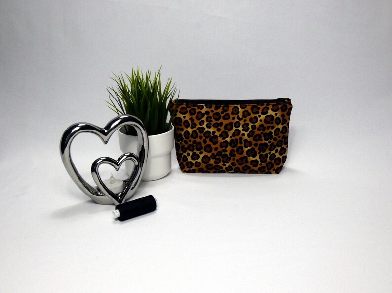 make up bag with a black zip with leopard print design on the fabric.