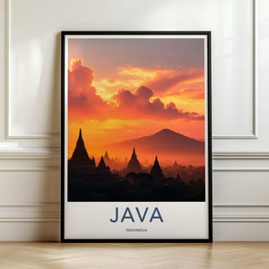 Könnte beinhalten: Ein gerahmter Kunstdruck mit einer Sonnenuntergangslandschaft aus Silhouetten alter Tempel auf Java, Indonesien. Der Himmel ist mit leuchtend orangefarbenen und gelben Wolken über einem Gebirge gefüllt. Der Text JAVA INDONESIA ist in Blau gedruckt.