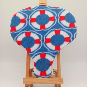 May include: A blue and red life preserver pattern fleece fabric on a wooden easel. The fabric is displayed on a small wooden easel with a Daler-Rowney label.