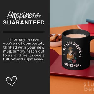 May include: Black ceramic mug with the text "NOT YOUR DADDY'S WORKSHOP" and an illustration of a woman welding. The mug is filled with a light-colored beverage and sits on a red tray. The image also includes text that says "Happiness GUARANTEED".