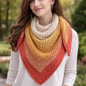Peut inclure: Un châle triangulaire dans un dégradé de couleurs, allant du crème au jaune, à l'orange et au rouge. Le châle est crocheté avec un motif ajouré. La personne porte une chemise blanche à manches longues.