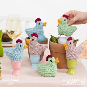 Peut inclure: Décorations de Pâques tricotées à la main représentant des poussins colorés. Les poussins, bleus, roses et verts, ont des crêtes rouges et des becs jaunes. Certains sont sur des coquetiers, d'autres dans de petits pots. Le texte "Hand-Knitted Joy" et "Easter Collection - Shop Now" est visible.