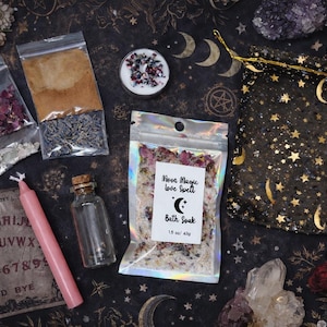 May include: An assortment of mystical items, including a pink candle, small glass bottle, and a bag labeled "Moon Magic Love Spell Bath Soak." Other items include bags of herbs, a star and moon-patterned bag, and a Ouija board.