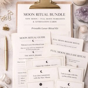 May include: A clipboard with a gold clip holds a "Moon Ritual Bundle" with worksheets and affirmation cards. The kit includes a guide, release rituals, and cards with affirmations. A pen, crystals, and a candle are also present.