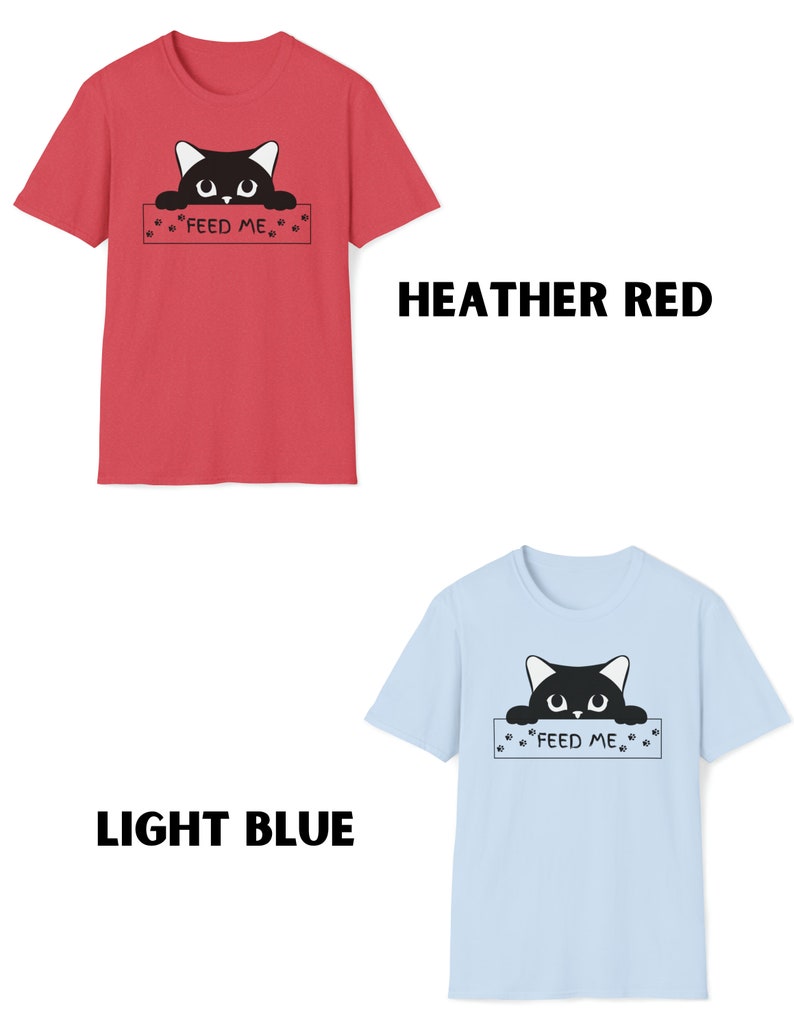 May include: Two t-shirts with a black cat peeking over a sign that says "Feed Me". The t-shirt on the left is heather red and the t-shirt on the right is light blue.