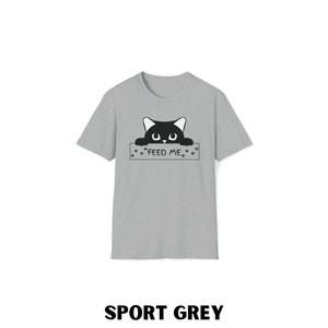 May include: A grey t-shirt with a black cat peeking over a sign that says "FEED ME".