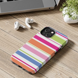 May include: A colorful striped phone case with a white background and orange, pink, green, and blue stripes. The case is designed for an iPhone 13 Pro.