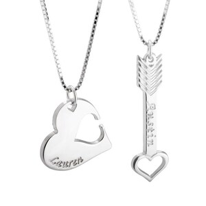 May include: Two silver necklaces with matching pendants. One pendant is a heart with a cutout in the shape of a smaller heart. The other pendant is an arrow with a heart at the bottom. The heart pendant says "Lauren" and the arrow pendant says "Austin".