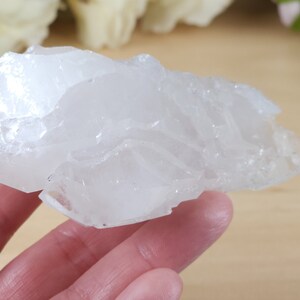 May include: A large, white, natural crystal cluster with a rough, textured surface. The crystal is translucent and has a milky white color.