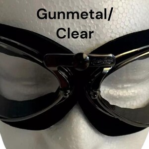 Puede incluir: Gafas de aviador de color gris oscuro con lentes transparentes y una correa negra ajustable. Gunmetal/Clear.