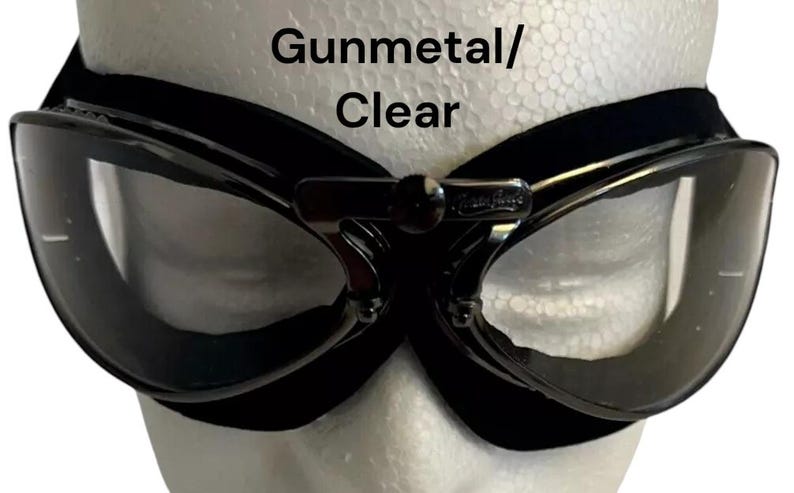 Puede incluir: Gafas de aviador de color gris oscuro con lentes transparentes y una correa negra ajustable. Gunmetal/Clear.