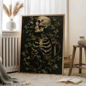 May include: A framed print of a skeletal figure surrounded by lush green foliage. The skull is visible and the skeleton is partially obscured by the leaves. The background is dark and the overall tone is moody.