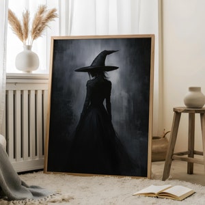 May include: A framed painting of a woman in a black dress and a pointed witch hat, standing in a dark, misty forest. The painting is in a wooden frame and is hanging on a white wall.