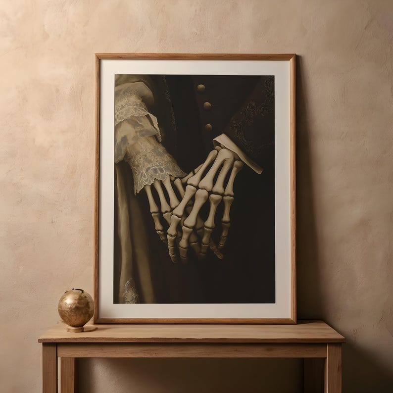 May include: Framed art print showing two skeletal hands holding each other. The image has a dark background with details of clothing and lace. The print is in a wooden frame, suitable for home decor.