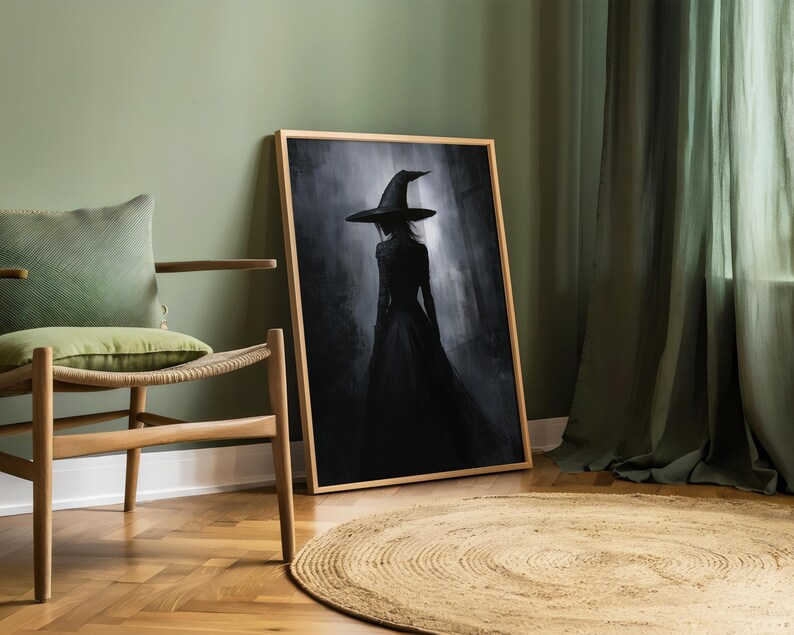 May include: A framed black and white illustration of a witch wearing a pointed hat and a long dress, standing in a dark forest. The image is set against a green wall and a wooden floor.