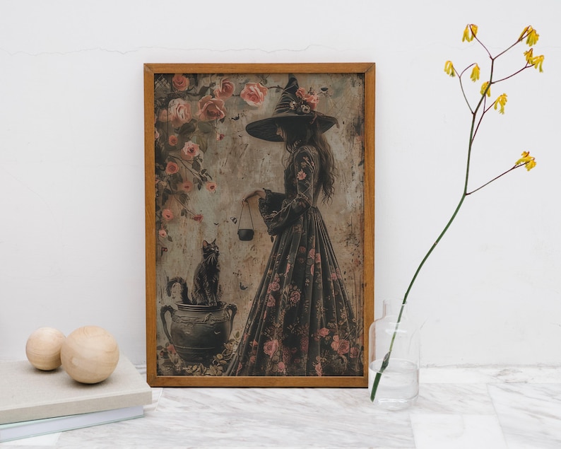 May include: A framed print of a witch in a black dress and a pointed hat, holding a cauldron. The witch is surrounded by pink roses and a black cat sits on a cauldron.