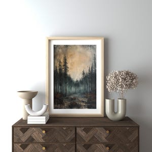 May include: A framed painting of a forest scene with tall, dark trees and a misty background. The sky is a soft orange and yellow, creating a warm and inviting atmosphere.