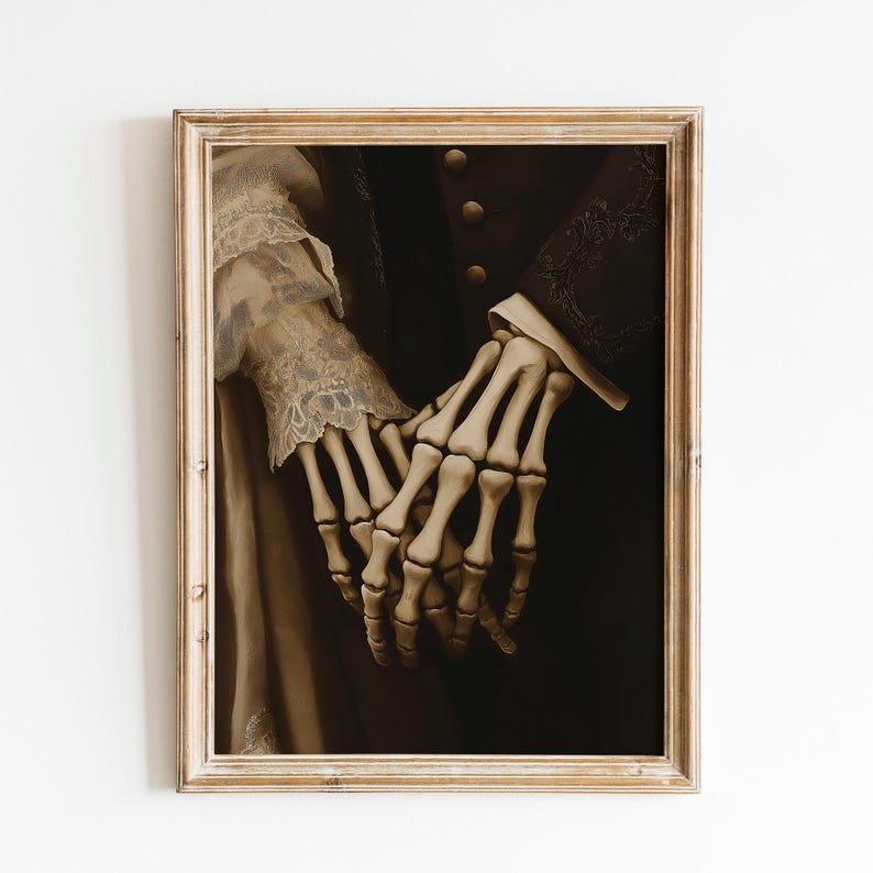May include: A framed sepia-toned artwork depicting two skeletal hands holding each other. The hands are the central element, set against a dark backdrop. The artwork is enclosed in a gold-coloured, ornate frame, giving it a vintage appearance.